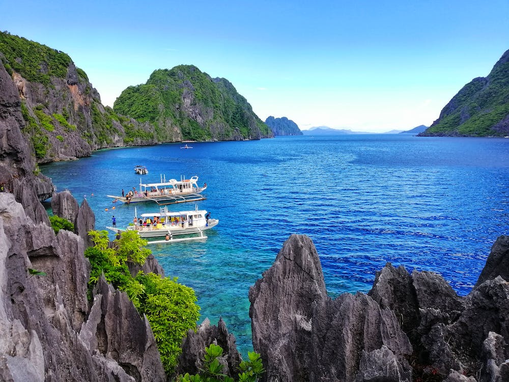 Free White Boats on Sea Near the Gray Rock Formation Stock Photo