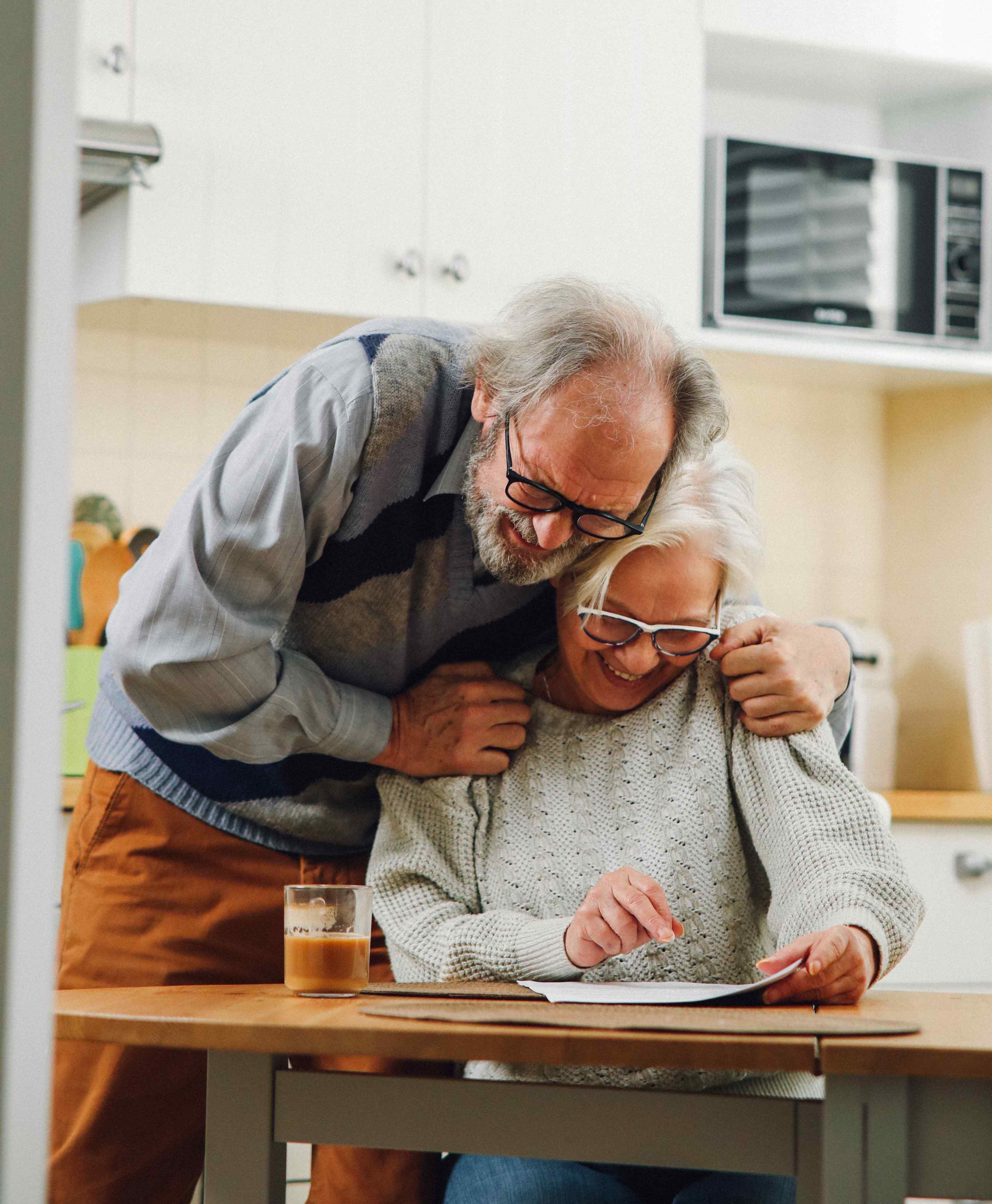 Image 4: An older couple stands together in a cozy kitchen, sharing a moment of joy and companionship amidst the warm surroundings.