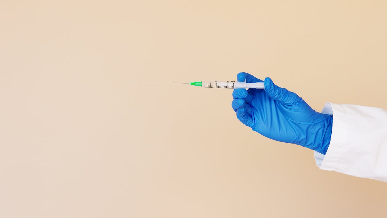 Free Crop nurse with syringe on beige background Stock Photo