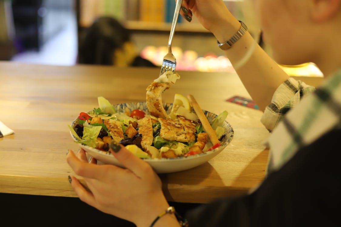 Free A Person Eating a Salad on a Plate Stock Photo