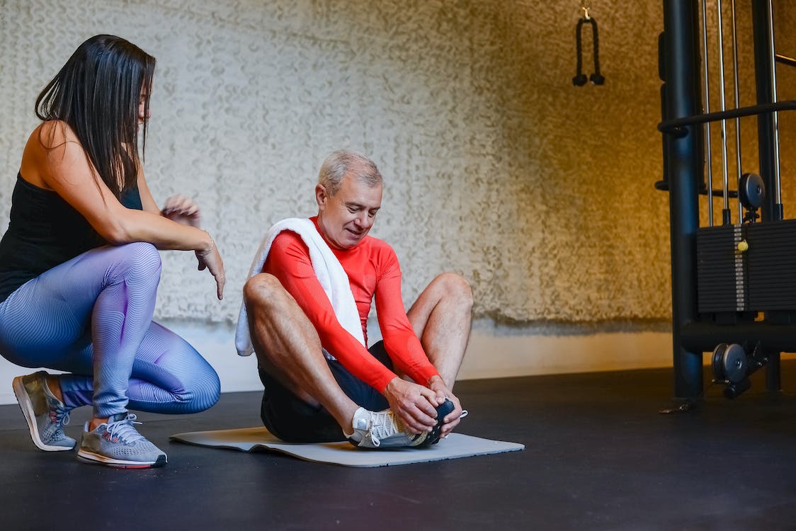 Free A Woman Training an Elderly Man Sitting on Yoga Mat Stock Photo