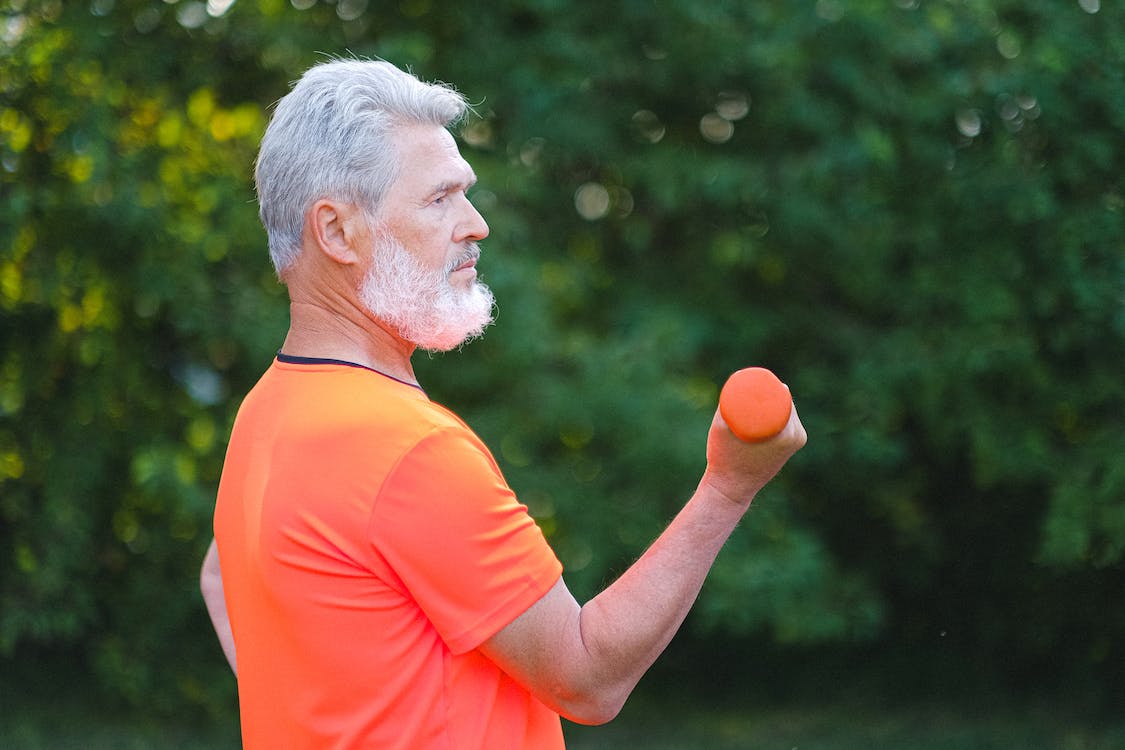 Free Aged man in sportswear training with dumbbells Stock Photo