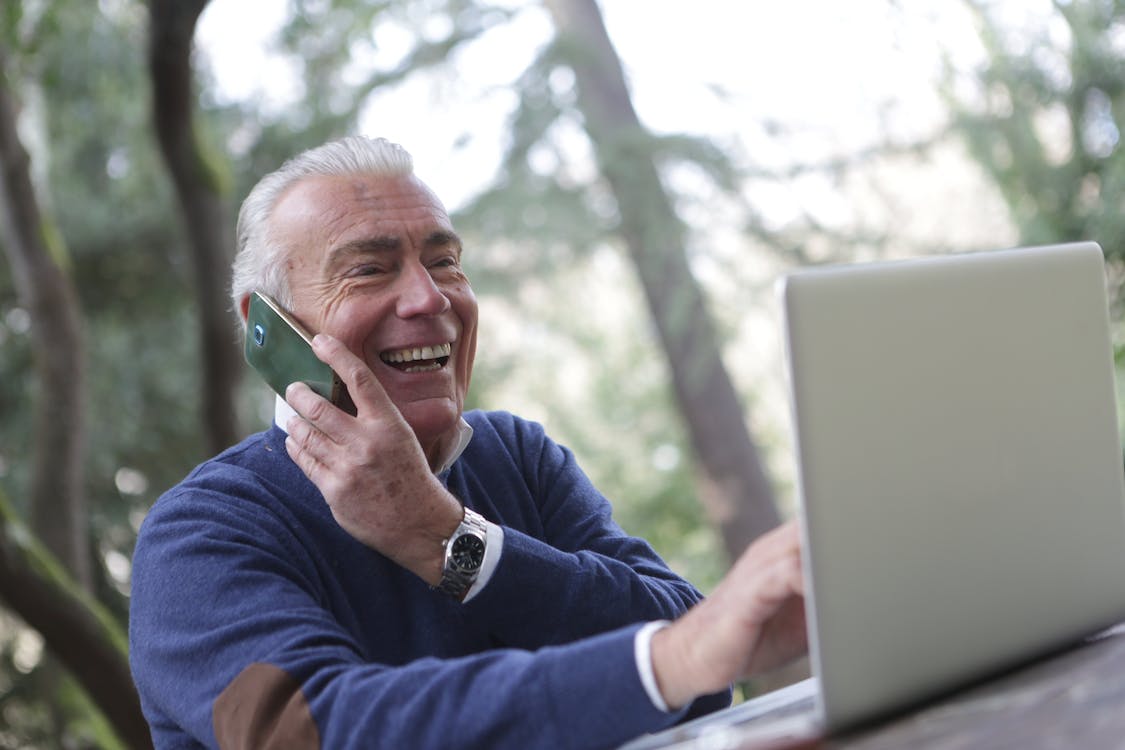 Free Man in Blue Long Sleeve Sweater Using Cellphone Stock Photo